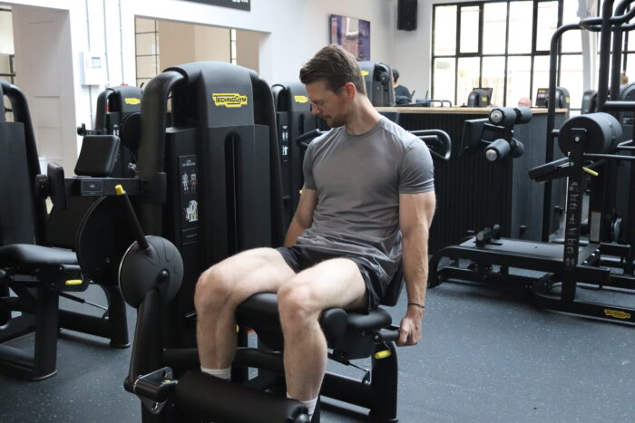 Personal trainer Wijnand Dijkshoorn voert de leg extension uit in sportschool Ceder Gym in Den Haag